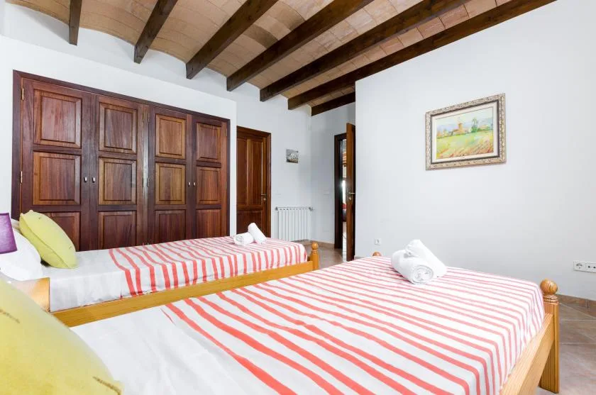 Un dormitorio con dos camas vestidas con ropa de cama a rayas rojas y blancas.
