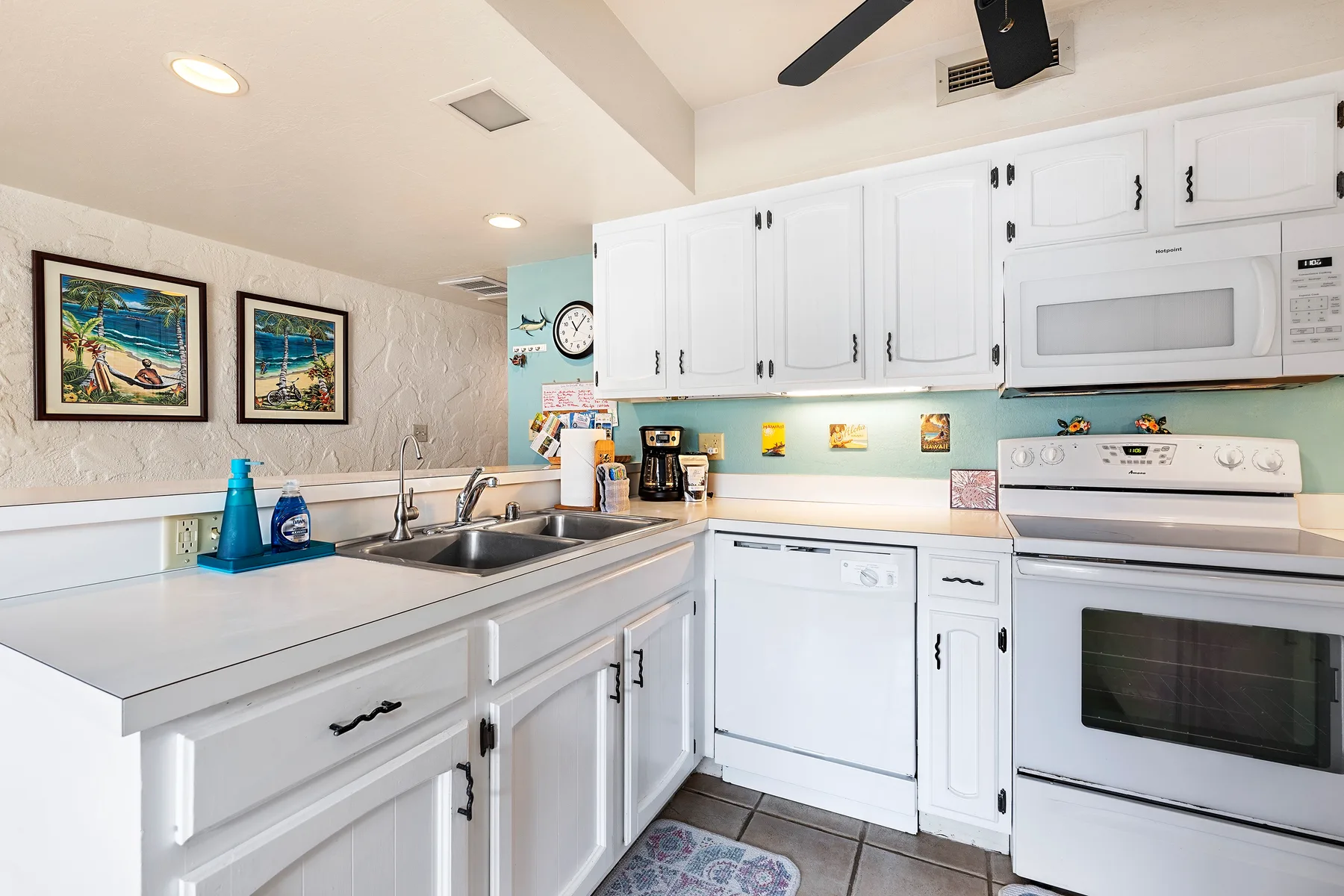 A bright kitchen with white cabinets, a sink, and a stove.