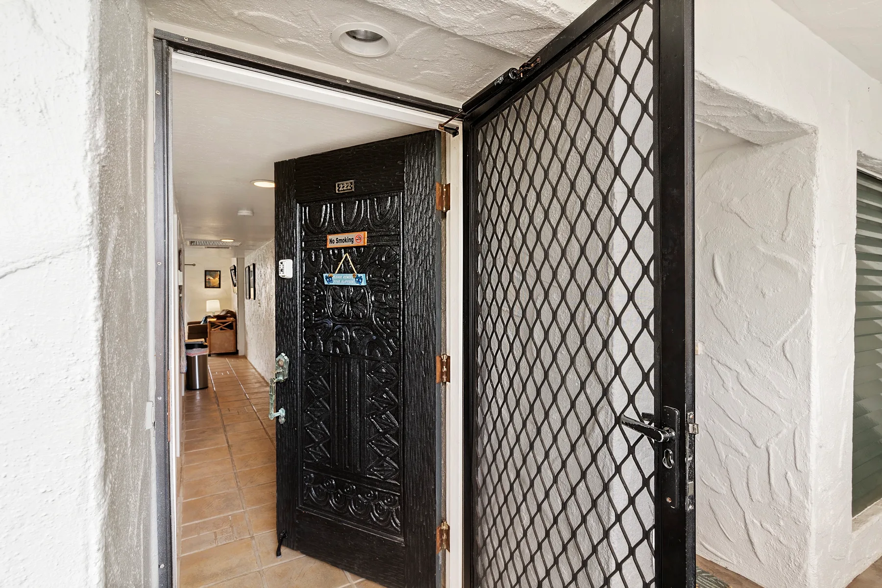 An open black security gate and doorway lead into a tiled interior.