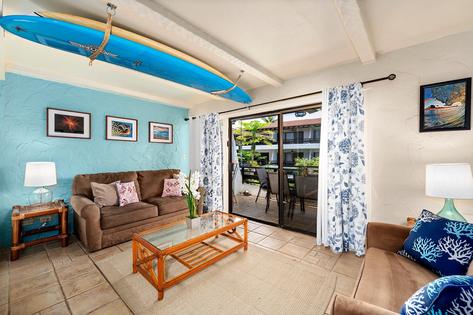 A living room with seating, a glass coffee table, and sliding doors opening to a patio.