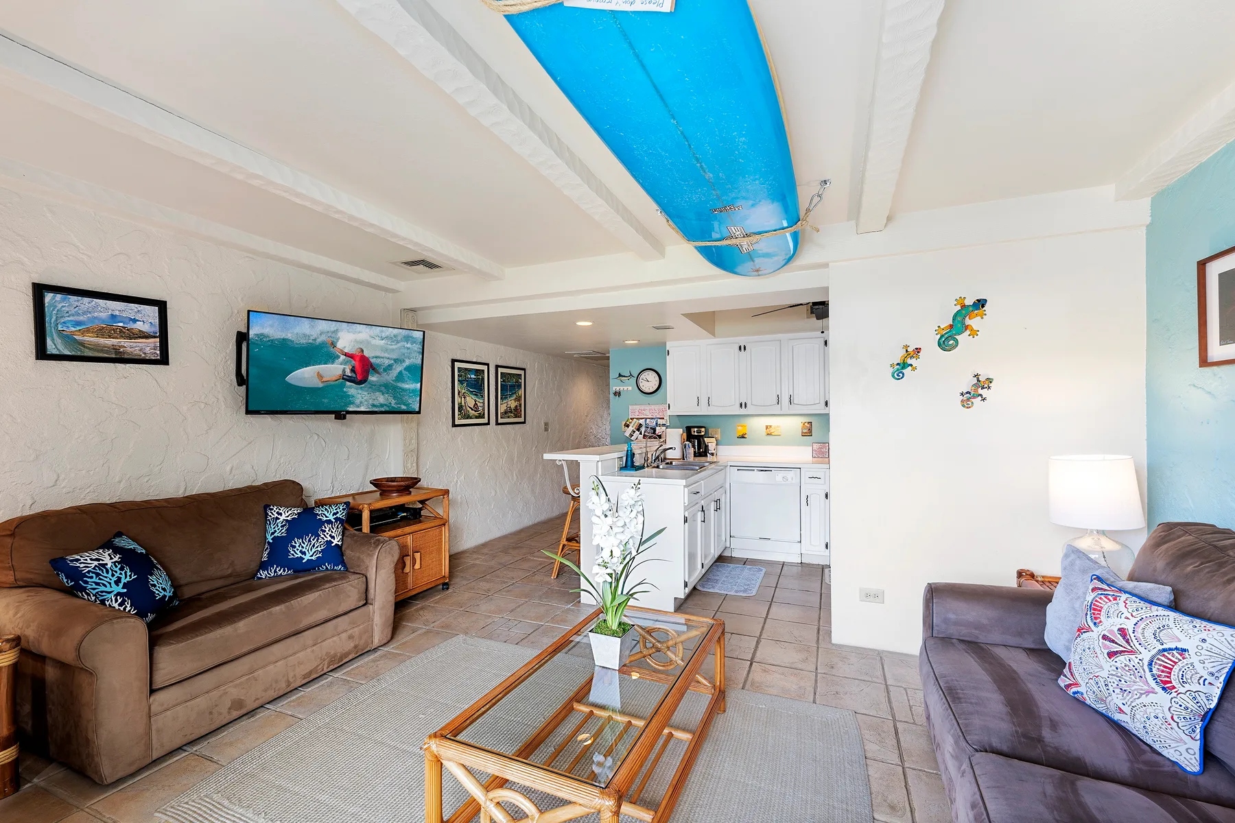 A living room with seating and a kitchen in the background.