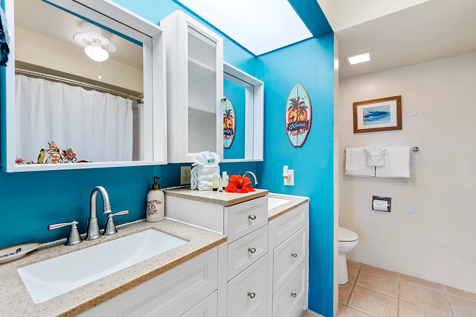A bright bathroom with a sink vanity, mirror, and shower curtain.