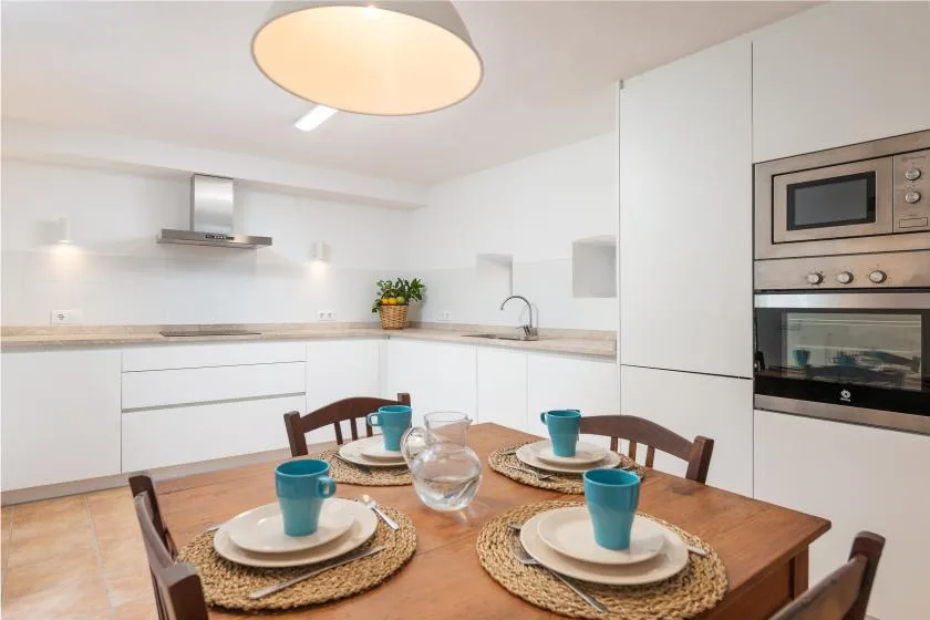 Una cocina luminosa con una mesa de madera puesta con platos y tazas.