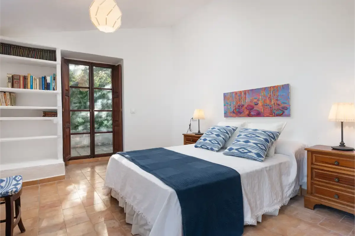 Un dormitorio con cama doble, mesitas de noche y estanterías empotradas.