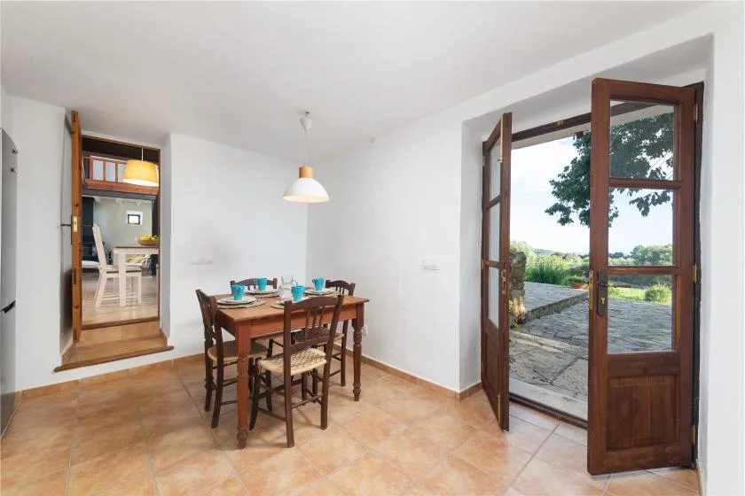 Comedor con una mesa de madera y una puerta abierta a una terraza.