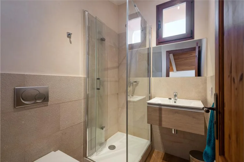 Un baño con una ducha de vidrio y un lavabo montado en la pared.
