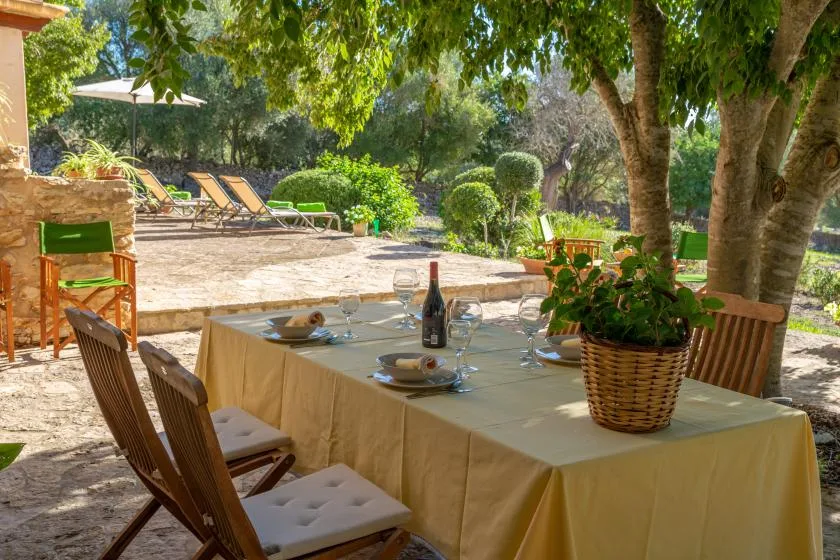 Comedor al aire libre con una mesa puesta bajo árboles frondosos.