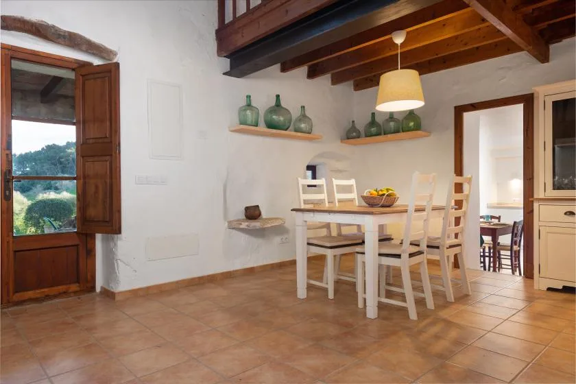Un comedor con una mesa blanca y sillas bajo vigas de madera vistas.