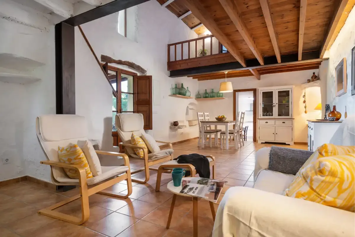 Una amplia sala de estar y comedor con asientos bajo vigas de madera a la vista.