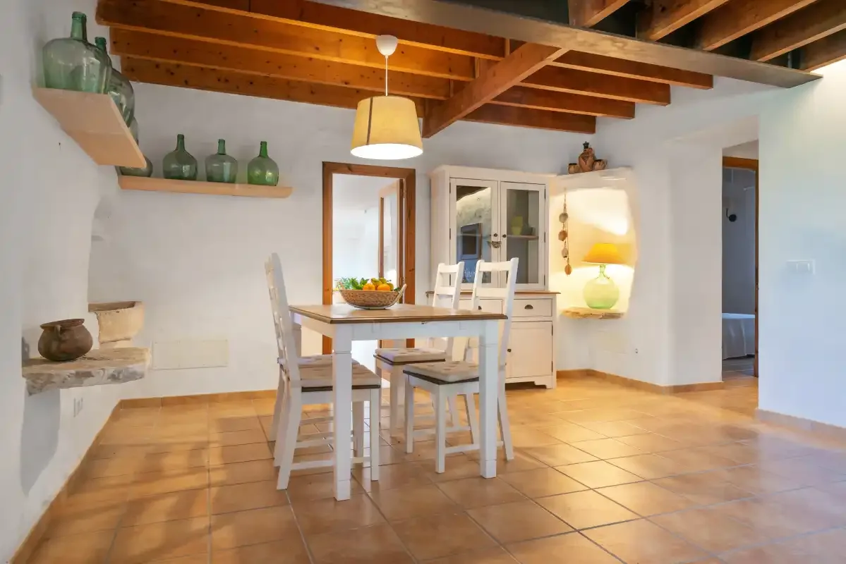 Comedor con una mesa bajo vigas de madera expuestas en el techo.
