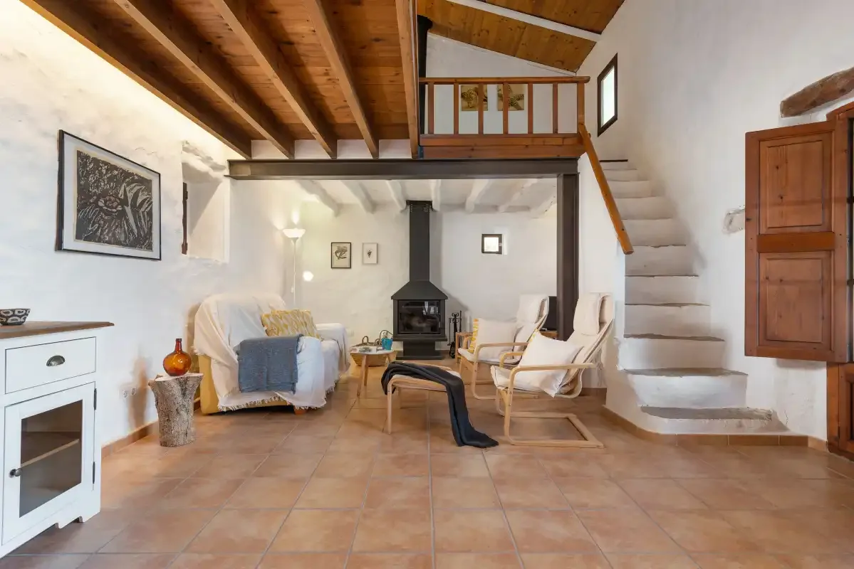 Un salón con asientos alrededor de una chimenea central bajo un techo de madera.