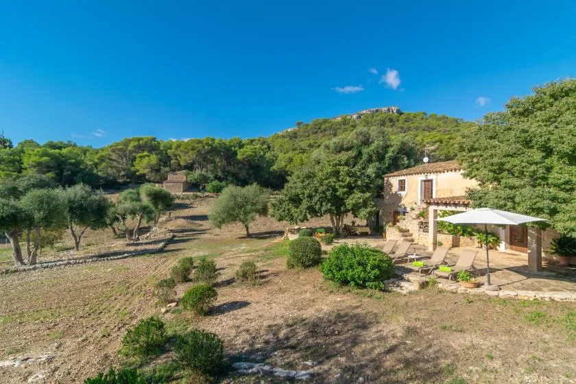 Una casa rural se encuentra junto a un paisaje seco salpicado de árboles.