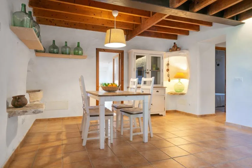 Comedor con una mesa y sillas bajo vigas de madera expuestas en el techo.