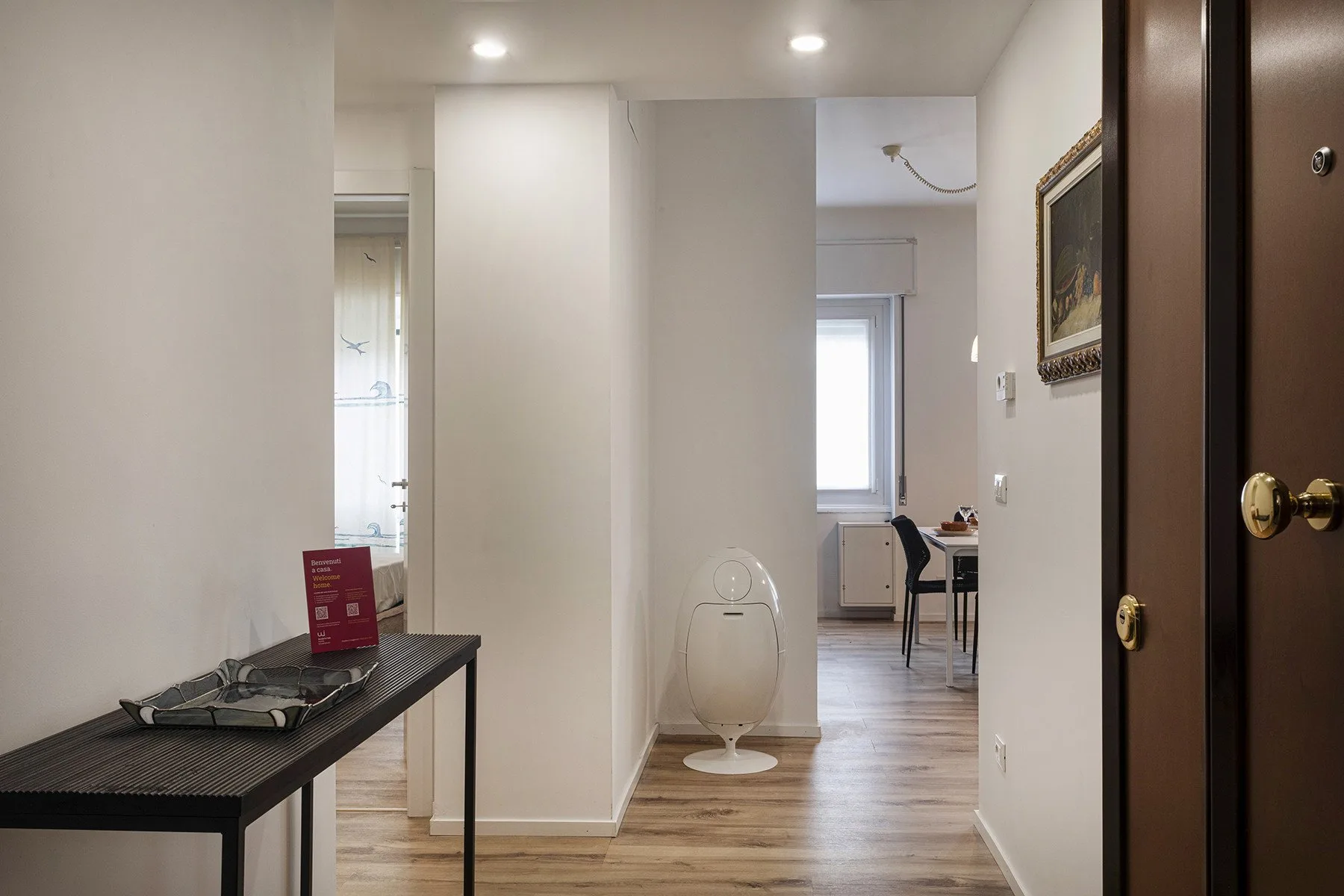 A hallway opens toward a bathroom and a dining area.