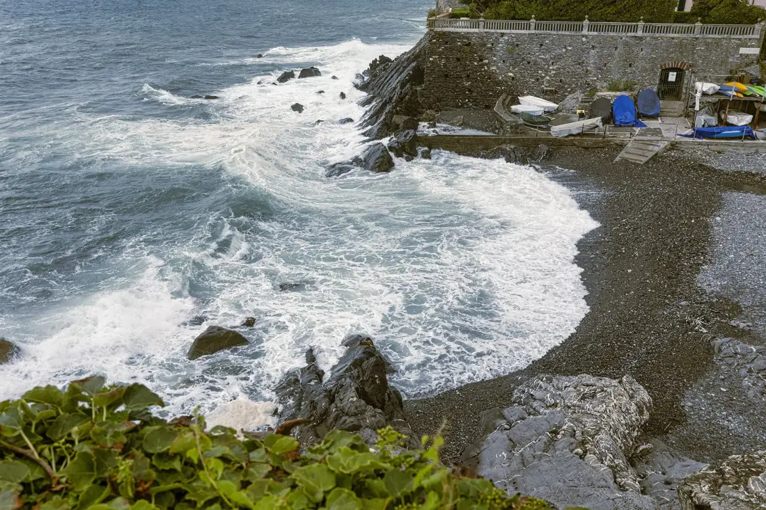 Waves wash over a rocky shoreline beside a pebbled beach.
