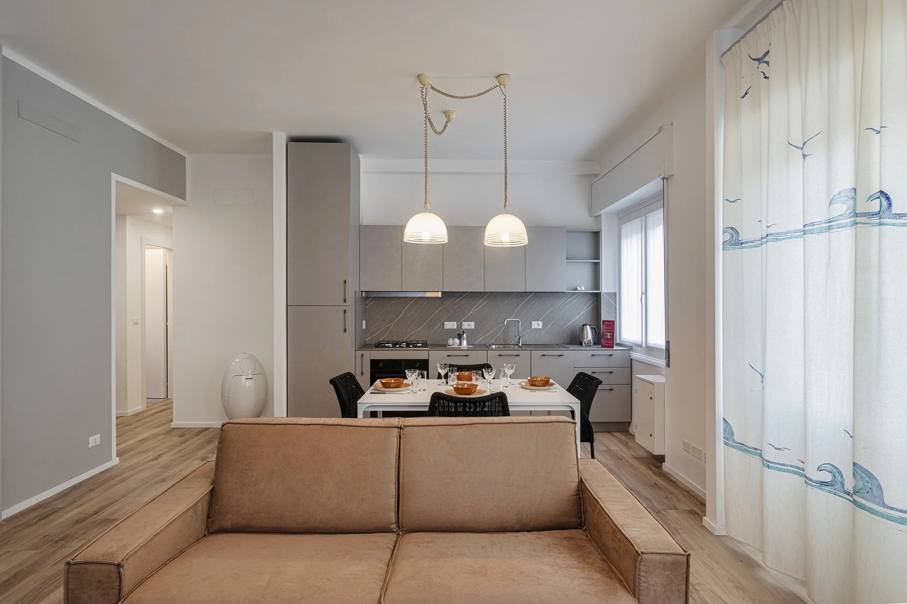 An open-plan living and kitchen area with a sofa in the foreground.