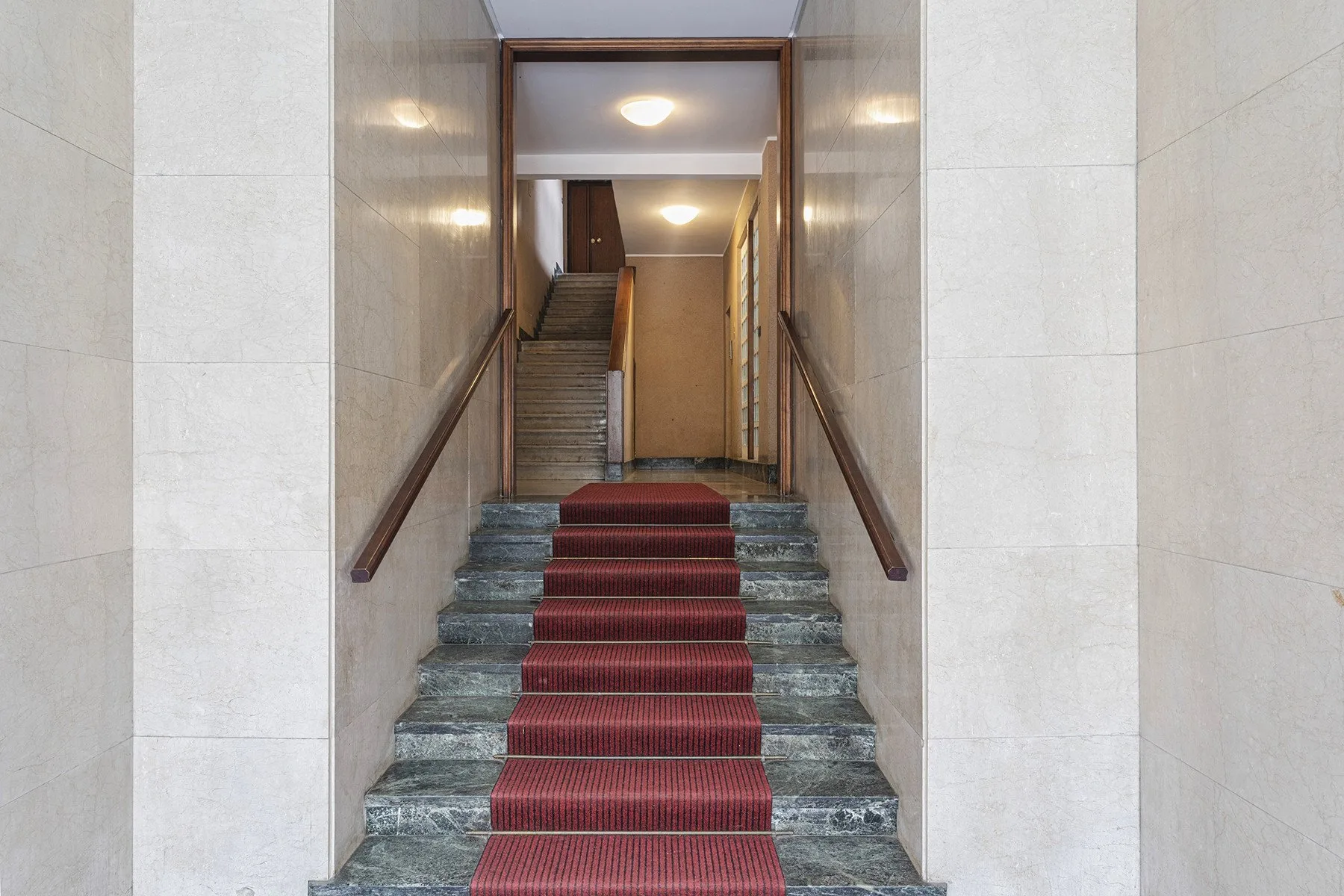 A tiled stairwell with a red runner leads to a landing.
