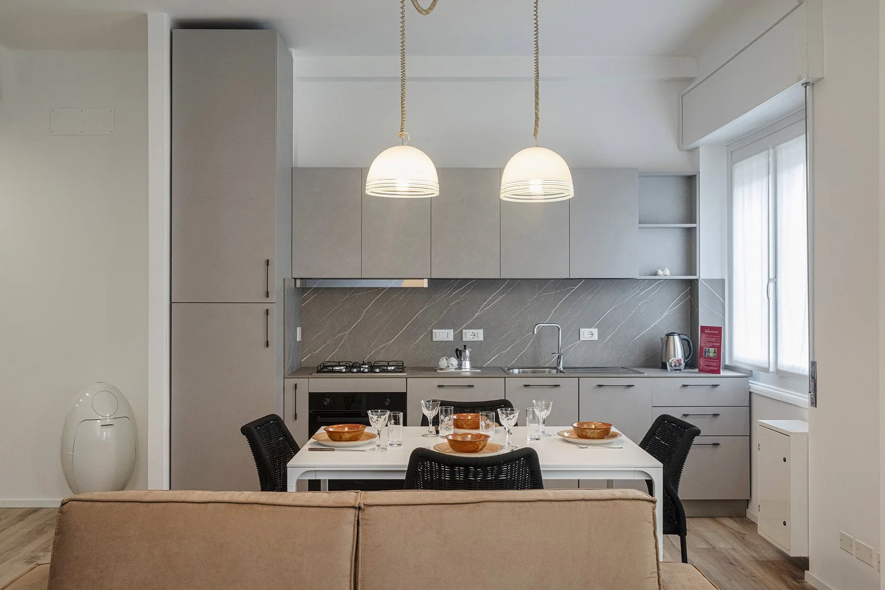 A modern kitchen and dining area with a table and pendant lights.