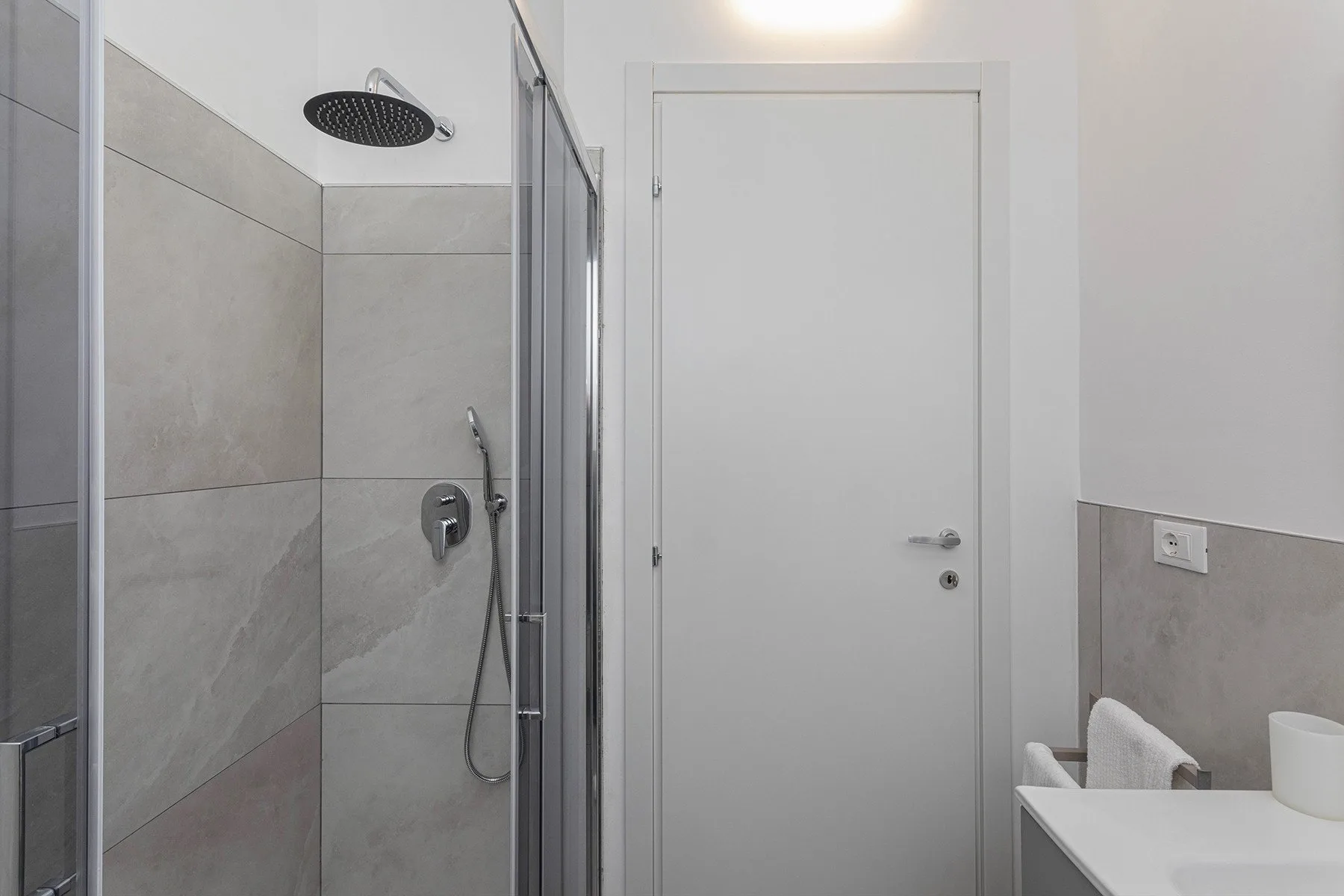 A bathroom with a shower beside a closed door.