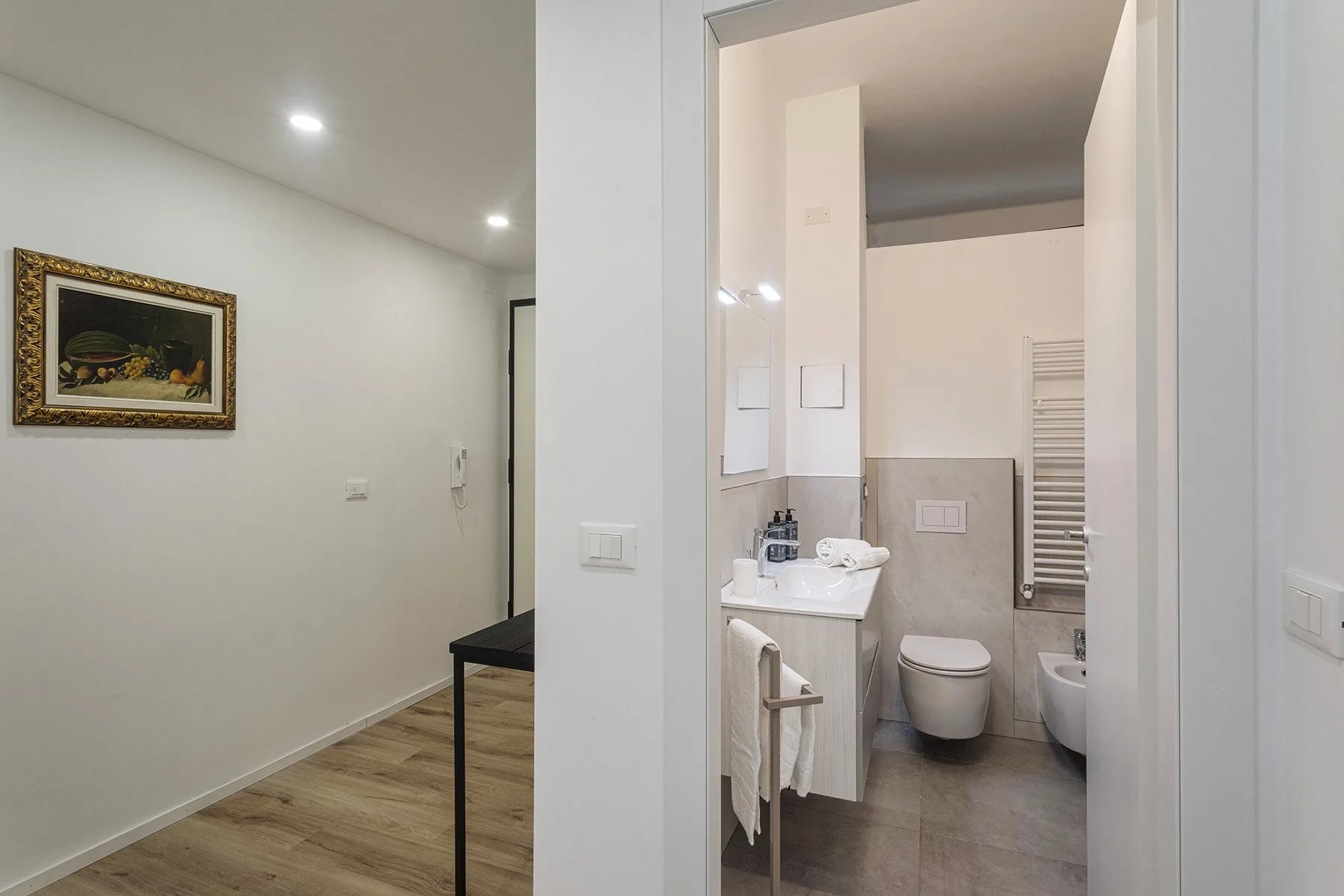 A bright interior hallway opens onto a bathroom with a sink and toilet.