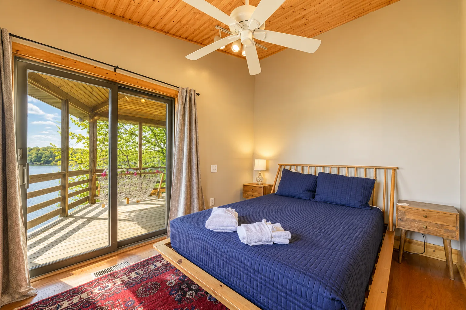 Un dormitorio con una cama azul junto a puertas corredizas de vidrio que dan a una terraza.