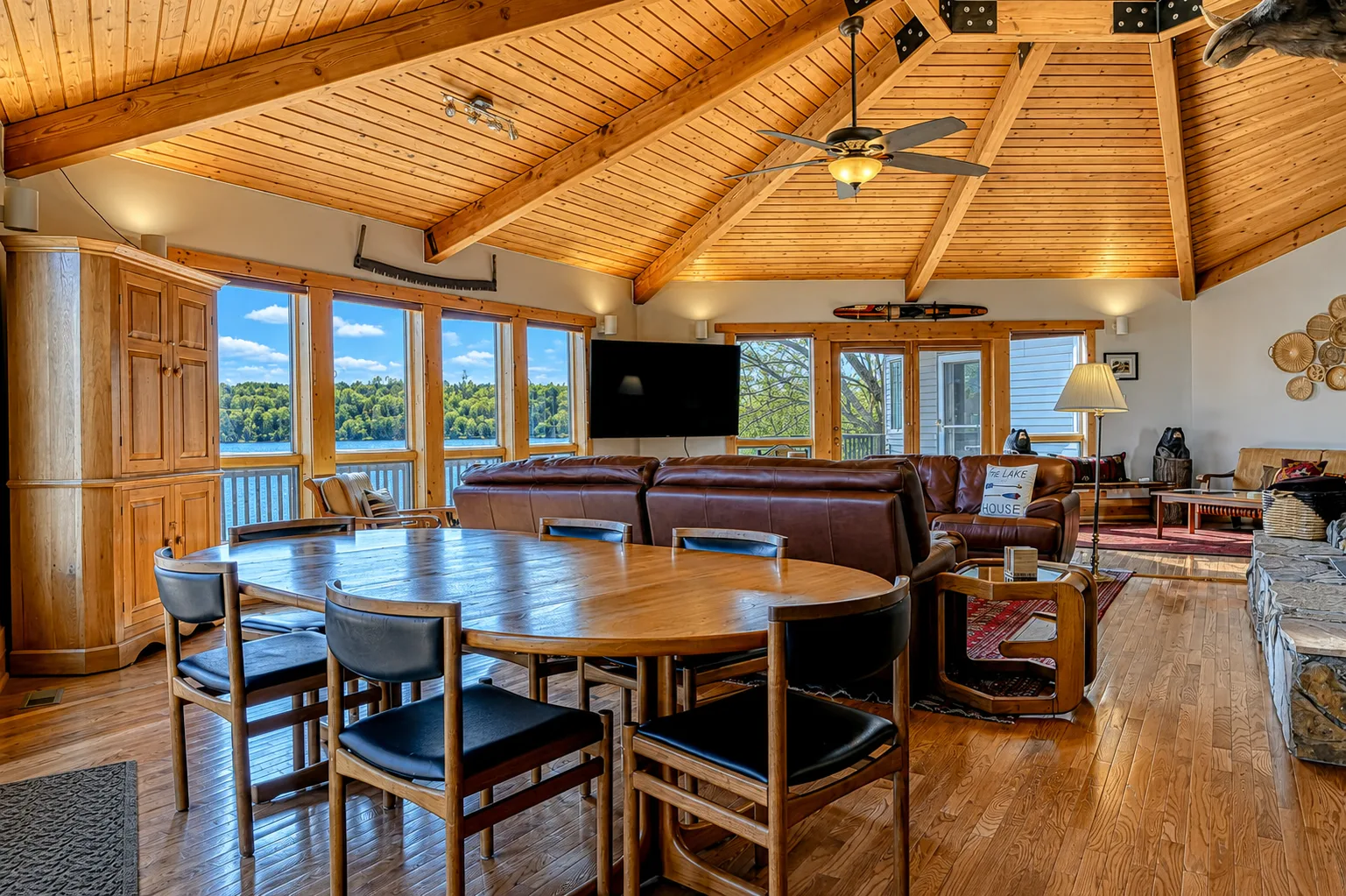 Una zona de comedor y estar con una gran mesa de madera bajo un techo abovedado de madera.