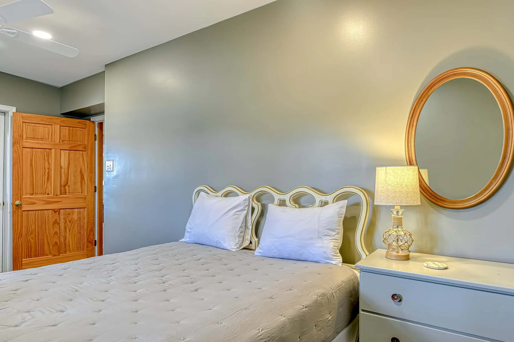 Un dormitorio con una cama, una puerta de madera y una mesita de noche.