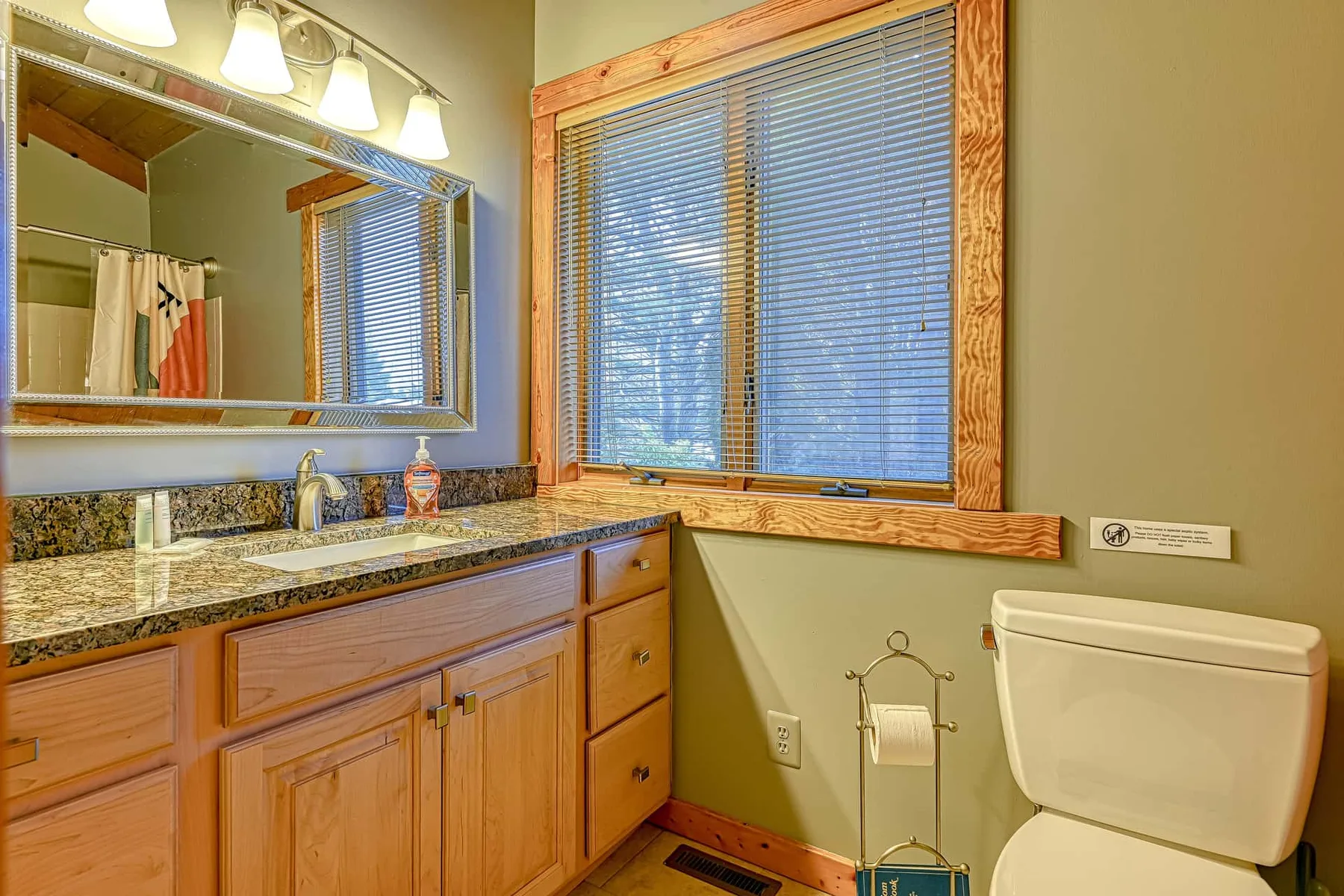 Un lavabo y un inodoro están junto a una ventana con persianas.