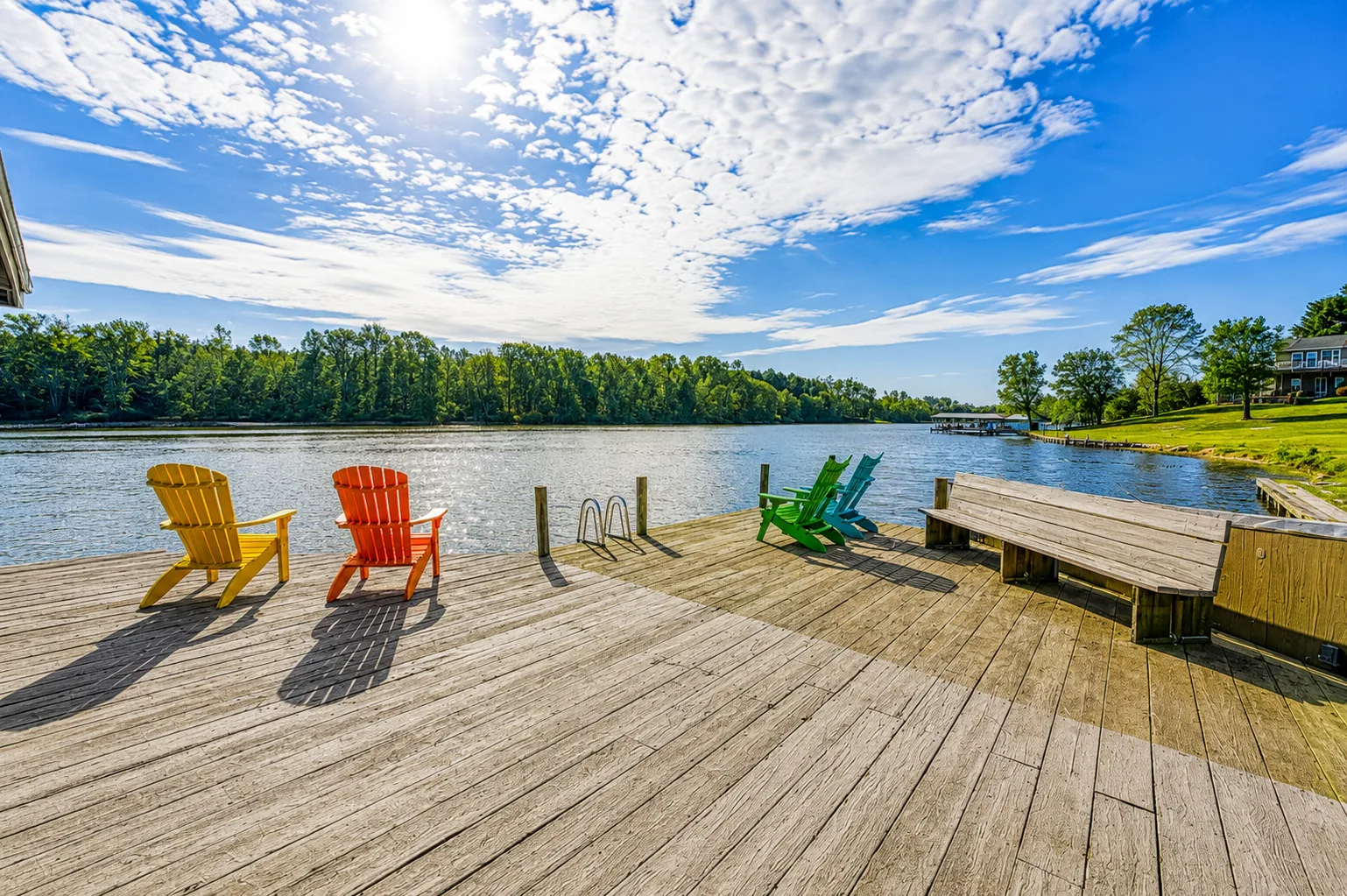 Una terraza junto al lago con sillas de colores y un muelle de madera junto al agua.