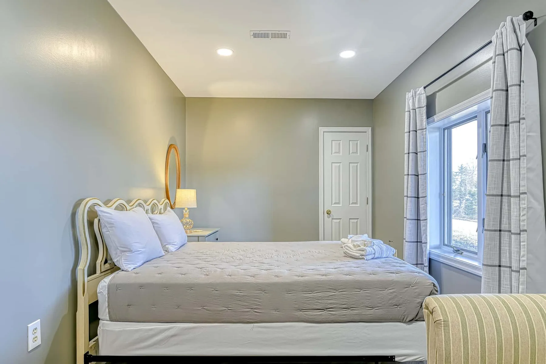 Un dormitorio con una cama junto a una ventana grande con cortinas.