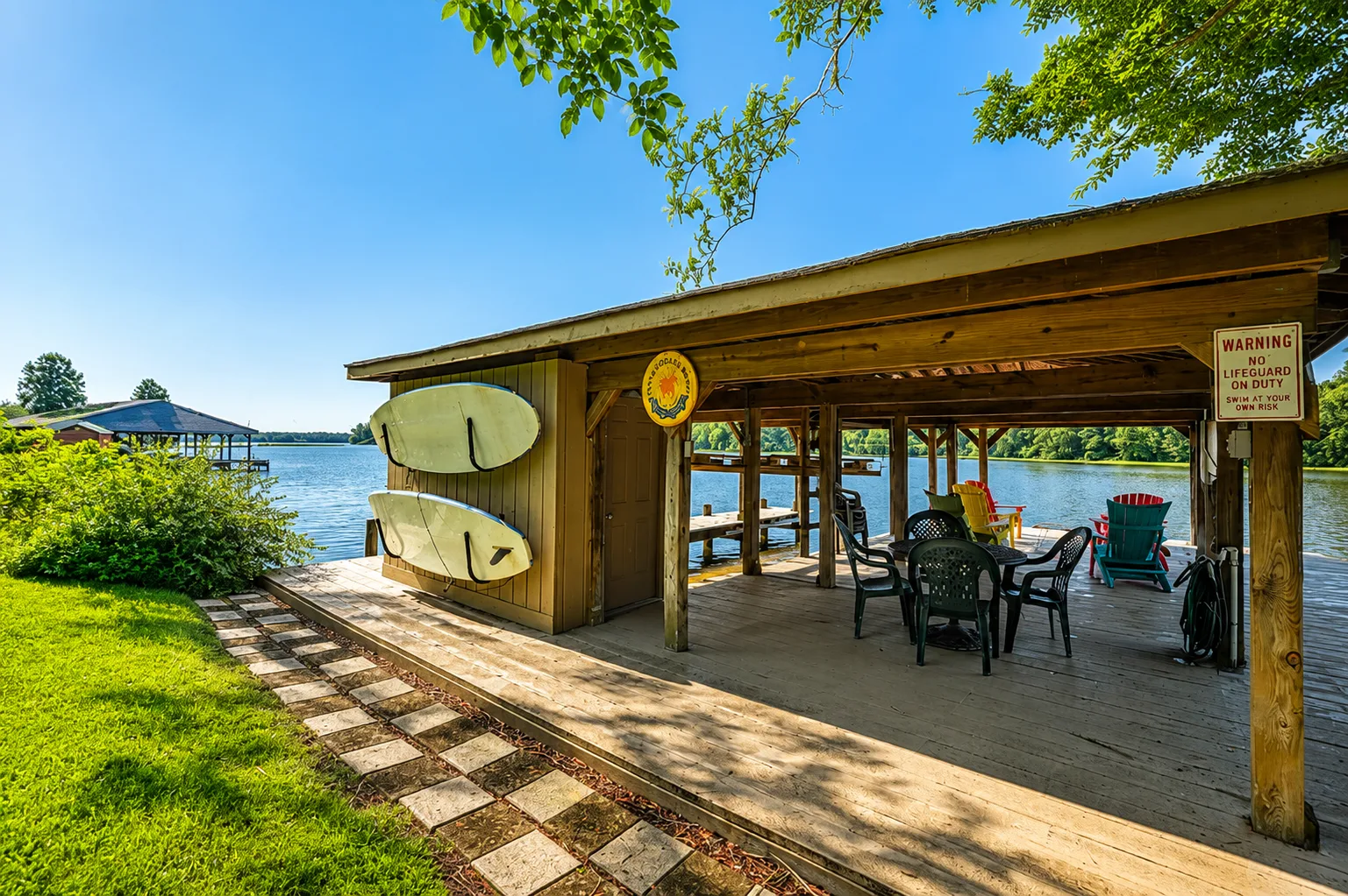 A covered lakeside pavilion with outdoor seating and boards mounted on the wall.