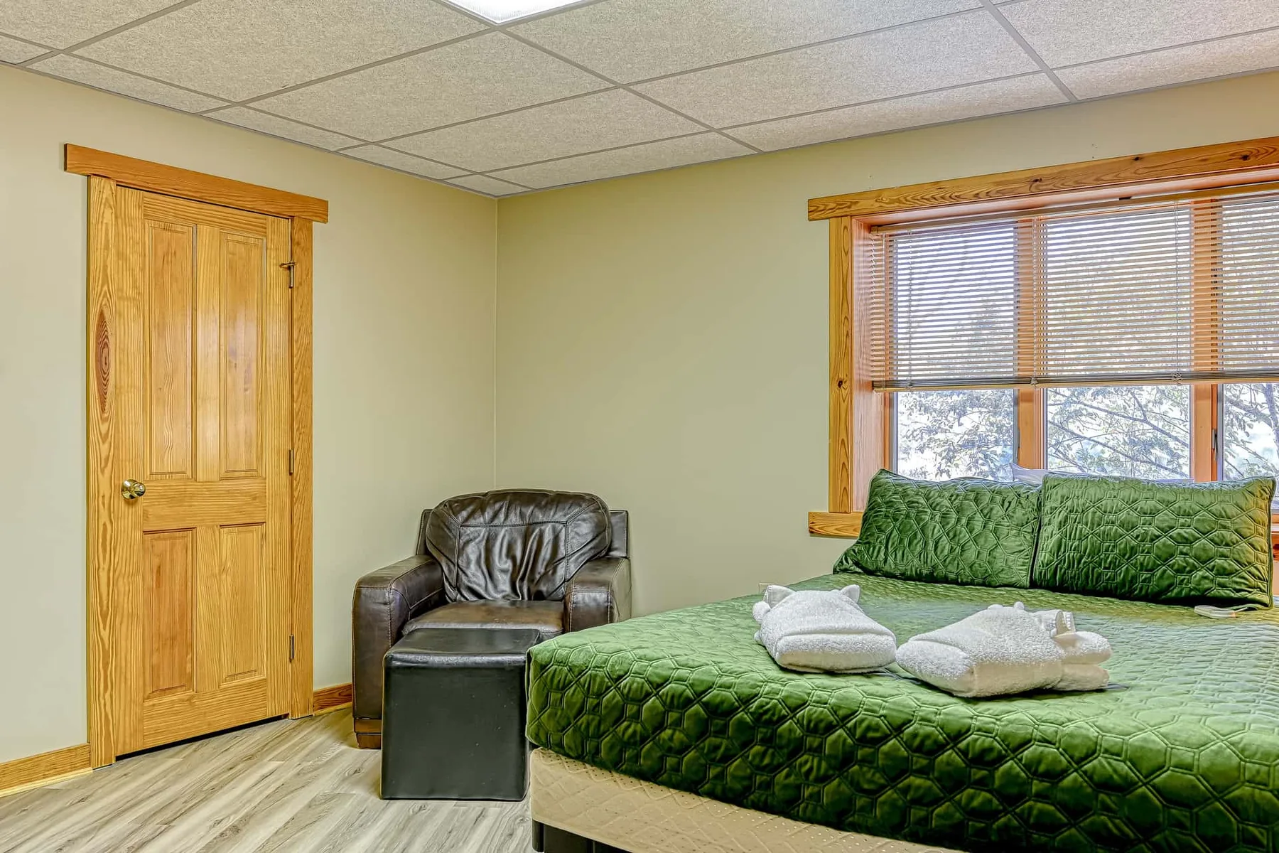 Un dormitorio con una cama verde, una ventana y una puerta de madera.
