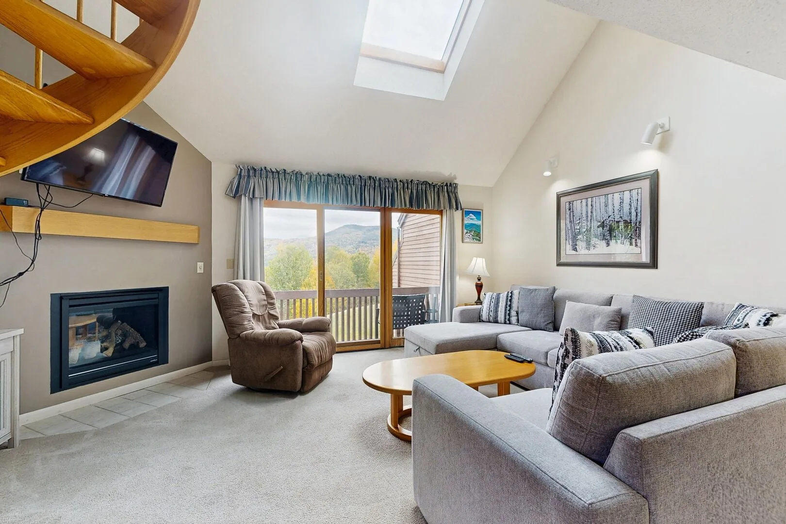 A bright living room with a sectional sofa, fireplace, and sliding glass doors to a balcony.