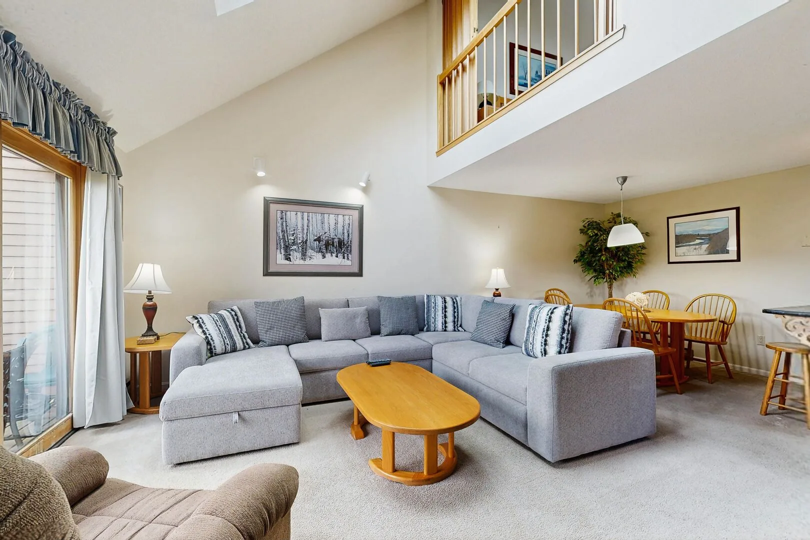 A bright living room with a large sectional seating area and a dining table.