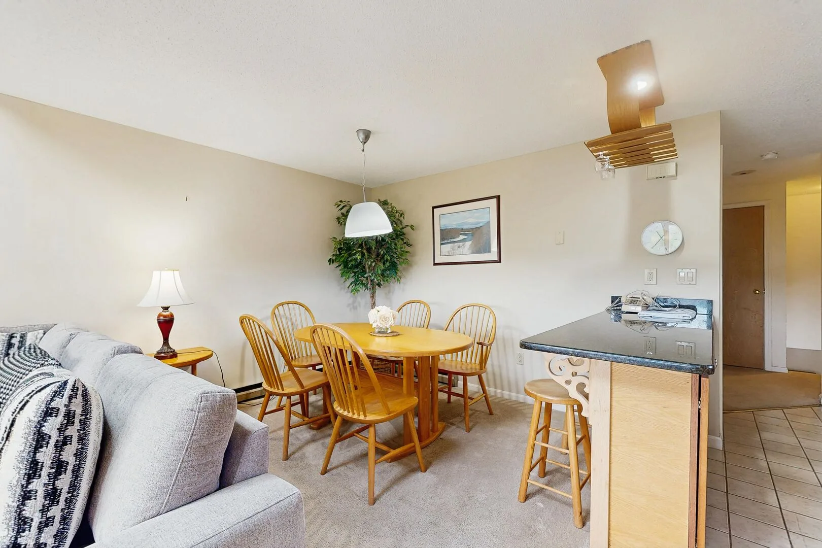 A dining area with a wooden table and chairs beside a kitchen counter.
