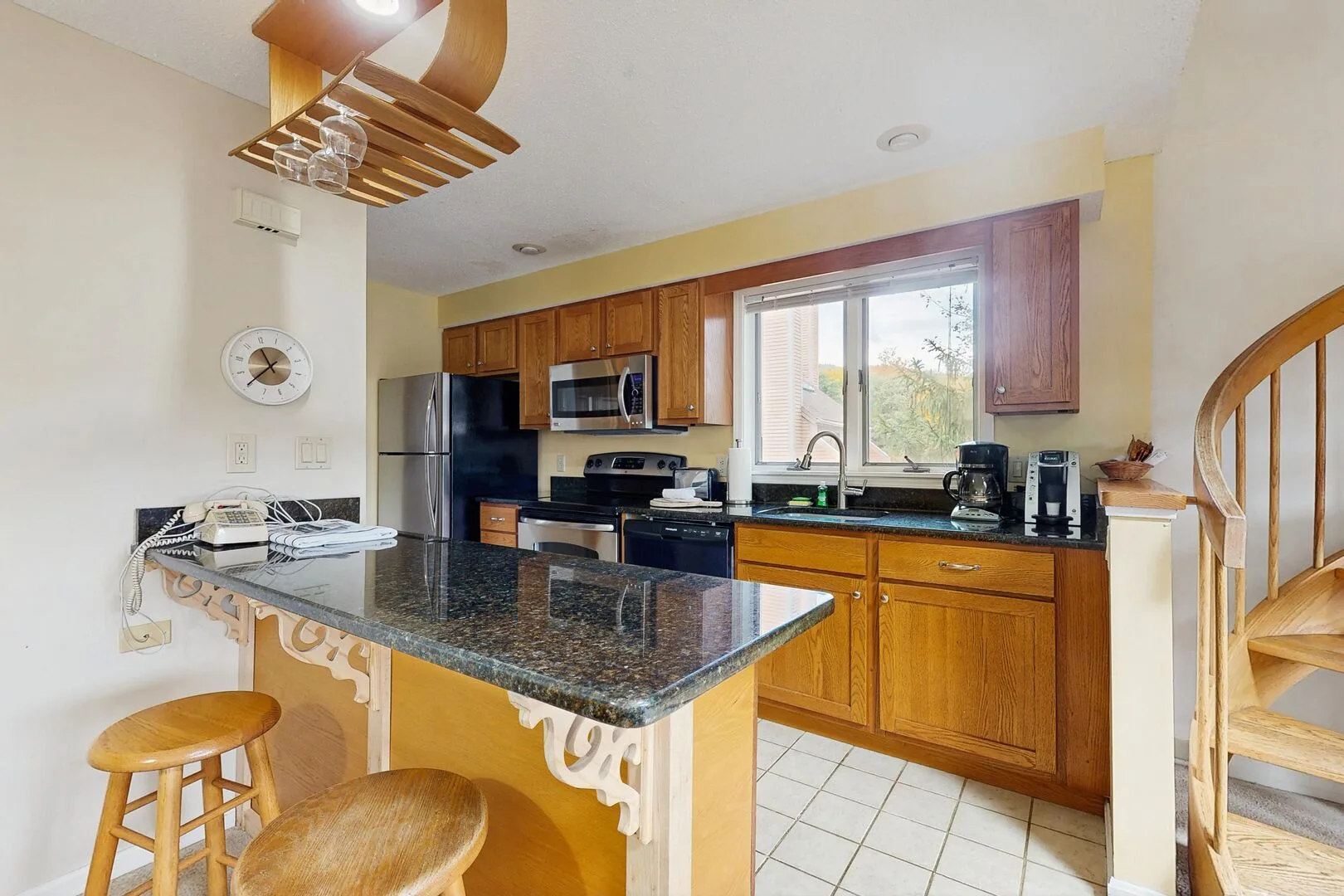 A bright kitchen with wooden cabinets, a dark countertop, and a window above the sink.