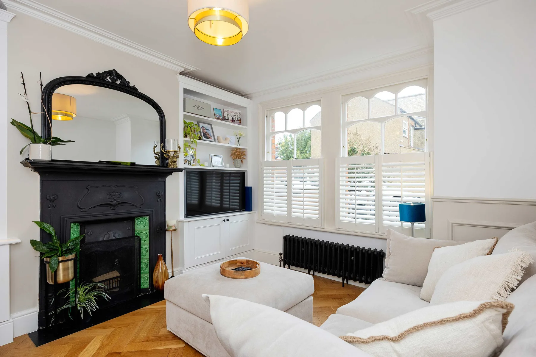 Una sala luminosa con chimenea, asientos blancos y ventanas grandes.