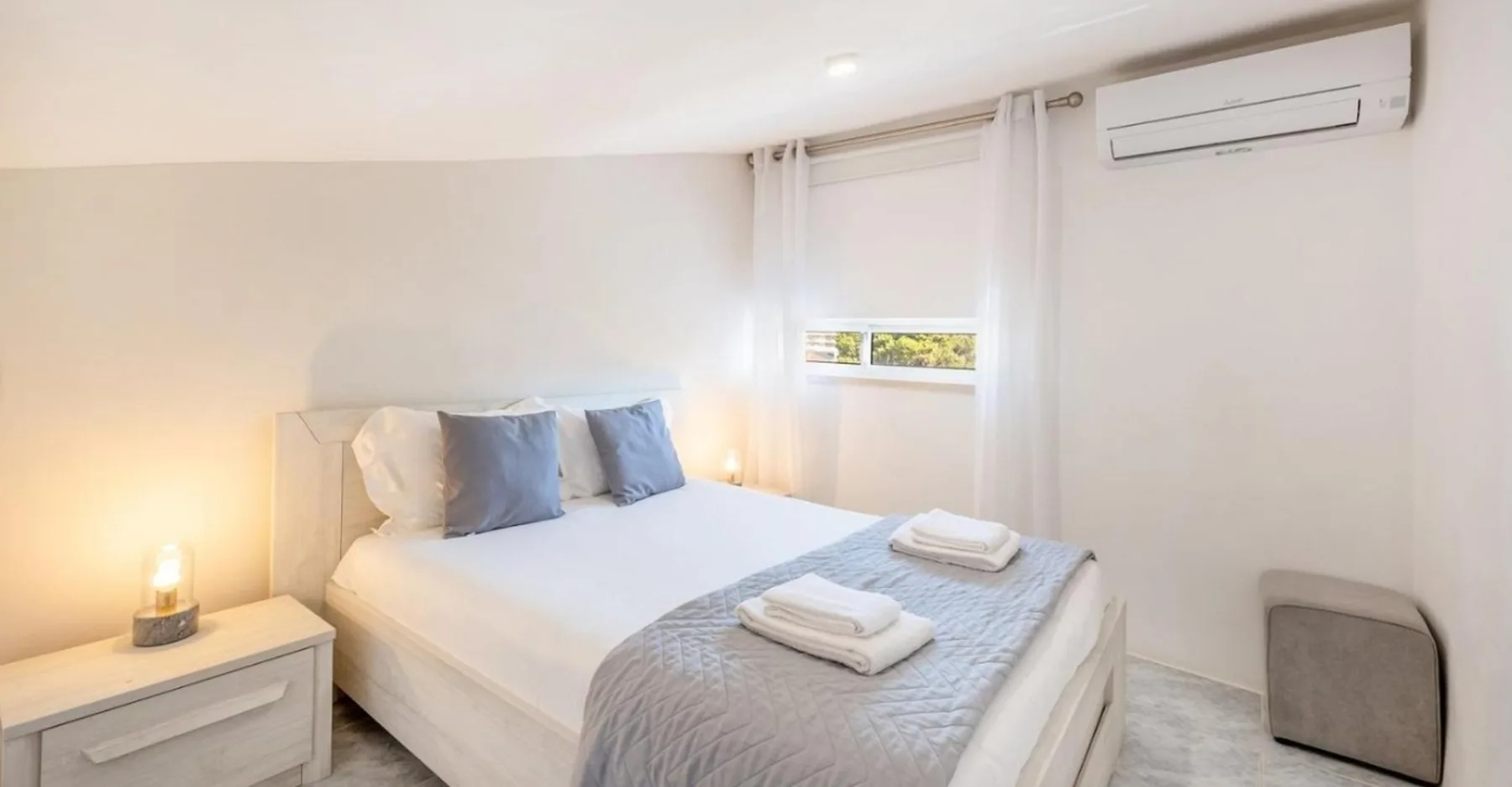 Un dormitorio con una cama bien hecha y una ventana.
