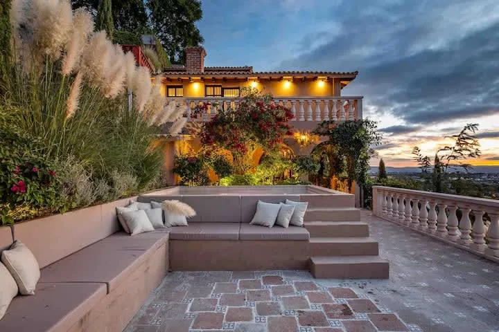 An outdoor terrace with built-in seating overlooks a landscaped garden at sunset.
