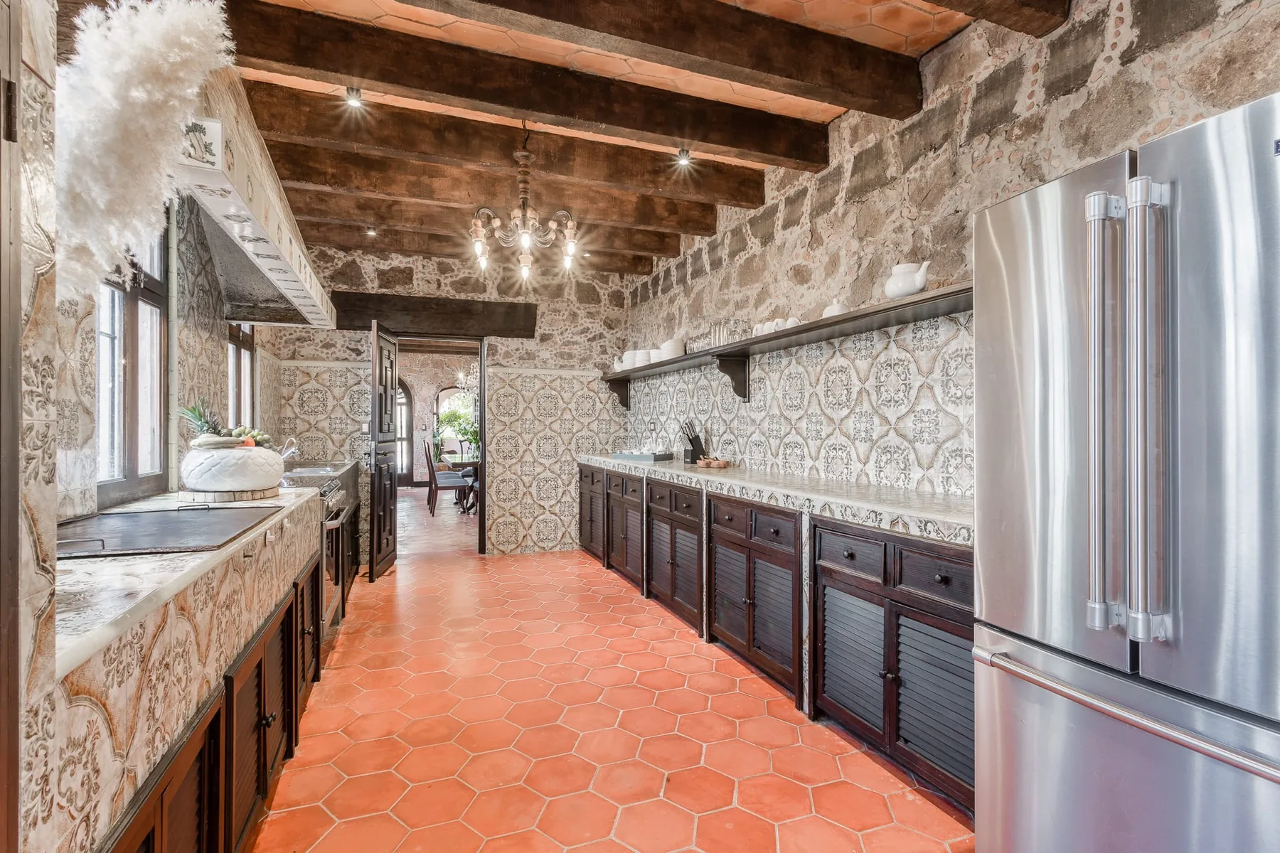 A rustic kitchen with stone walls, dark cabinets, and a tiled floor.