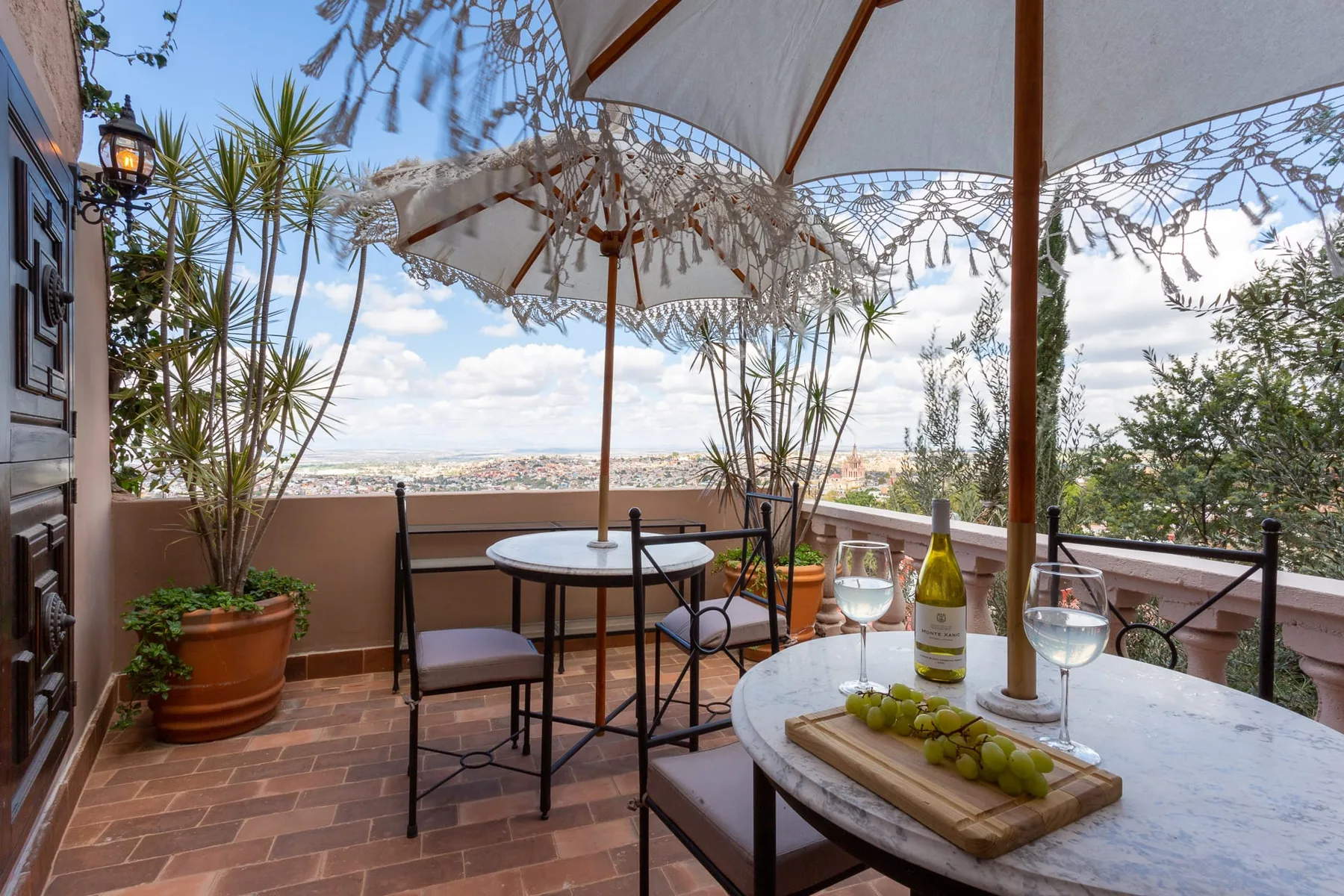 A terrace dining area with tables, chairs, and parasols overlooking the distant landscape.