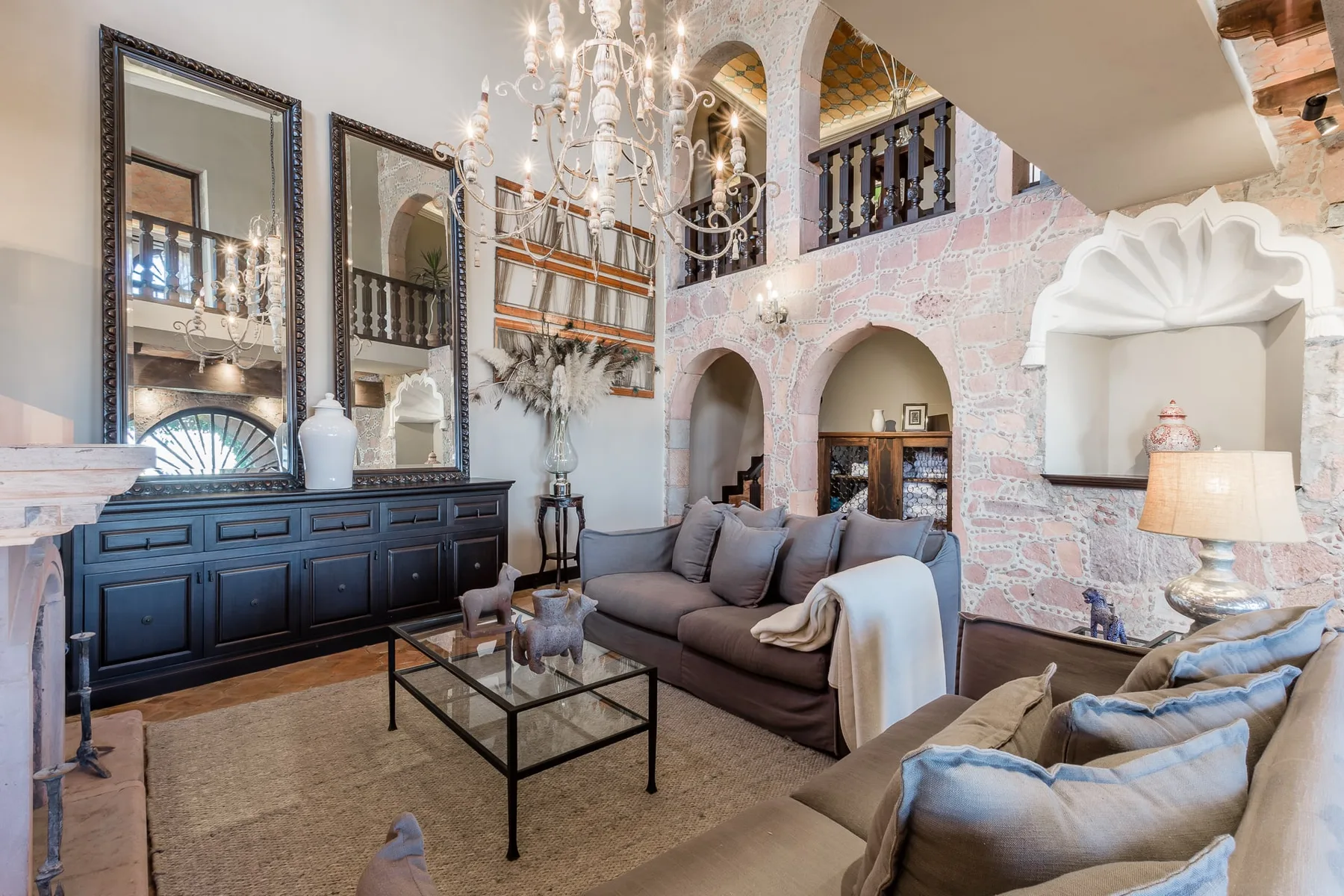 A living room with seating beneath a chandelier in a high-ceilinged interior.