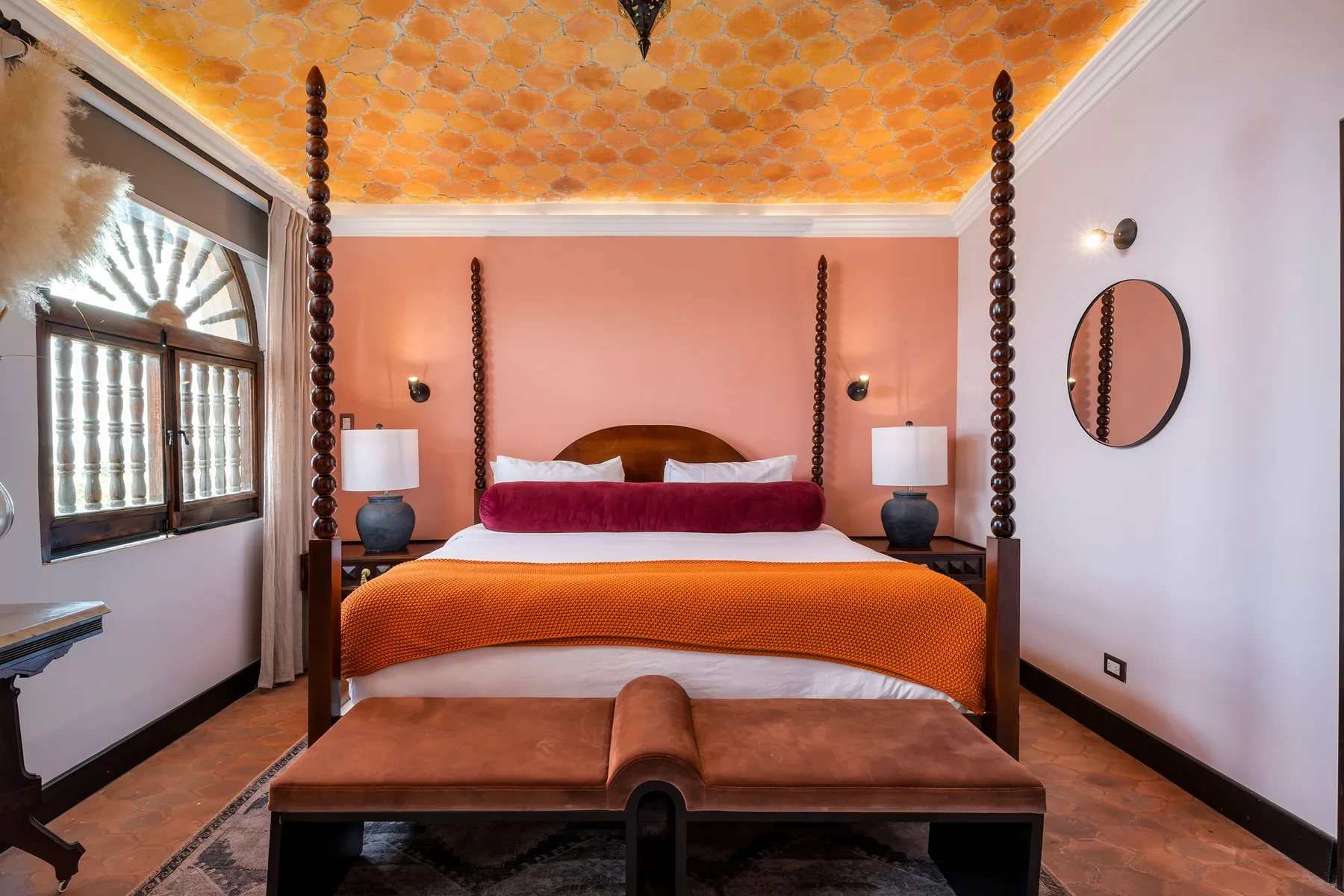 A bedroom with a wooden bed, orange bedding, and matching bedside lamps.