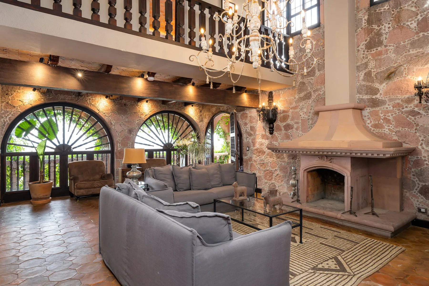 A spacious living room with gray seating, arched windows, and a large fireplace.