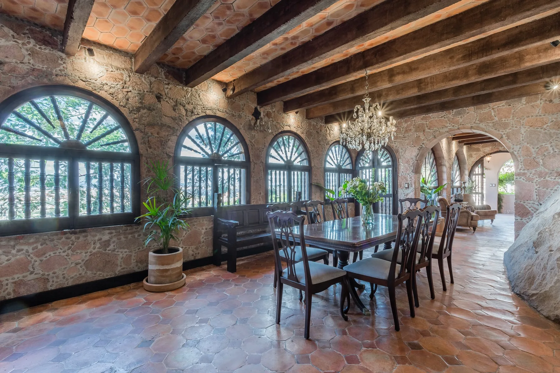 A rustic dining room with a long table beneath exposed wooden beams.