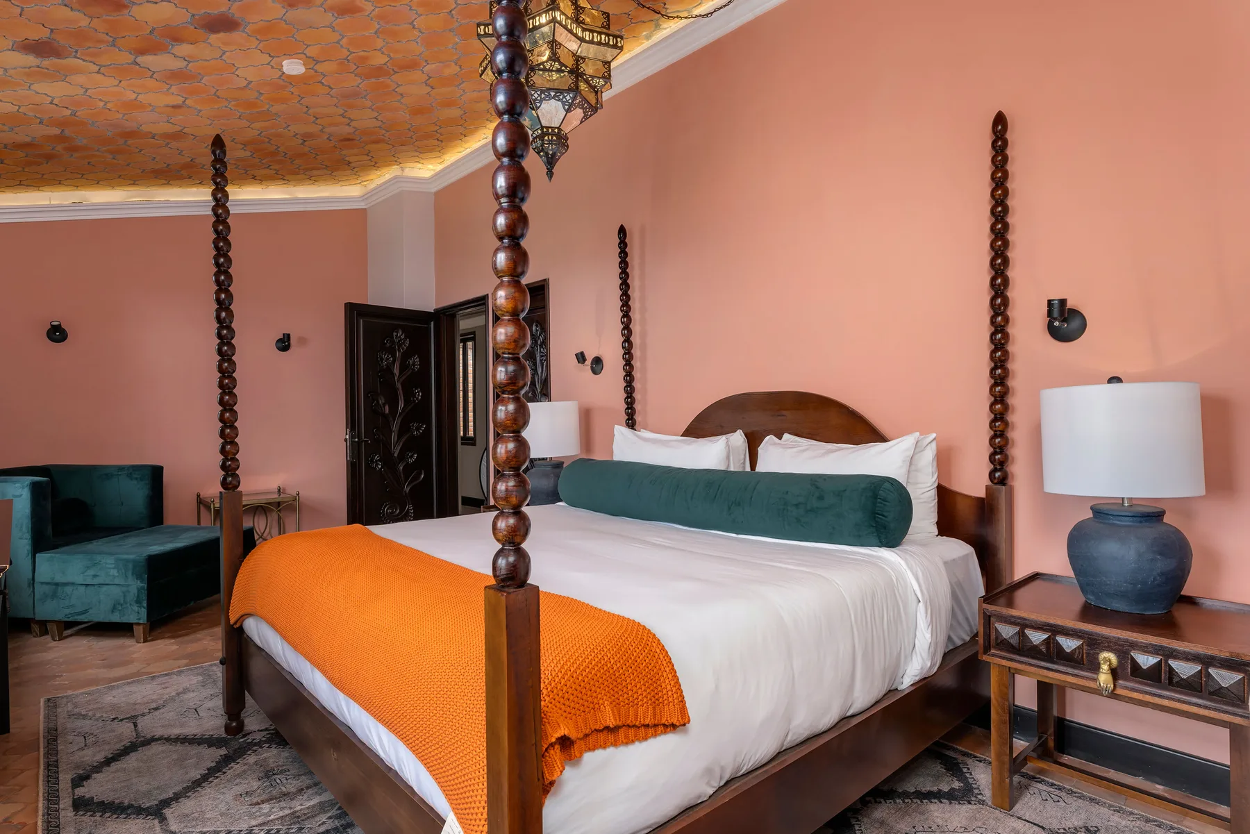 A bedroom with a wooden bed, white bedding, and an orange blanket.