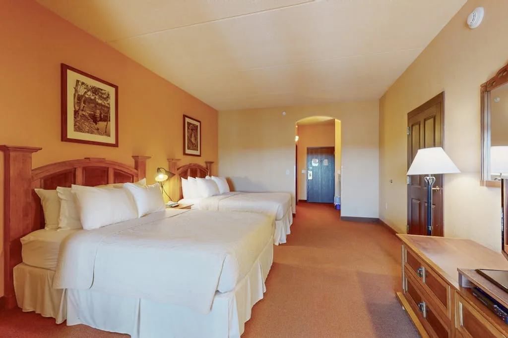 Un dormitorio con dos camas, ropa de cama blanca y muebles de madera.