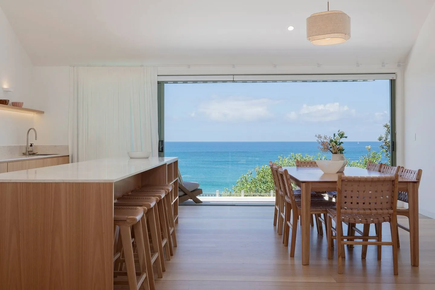 Un comedor luminoso da a un balcón con vistas al mar.