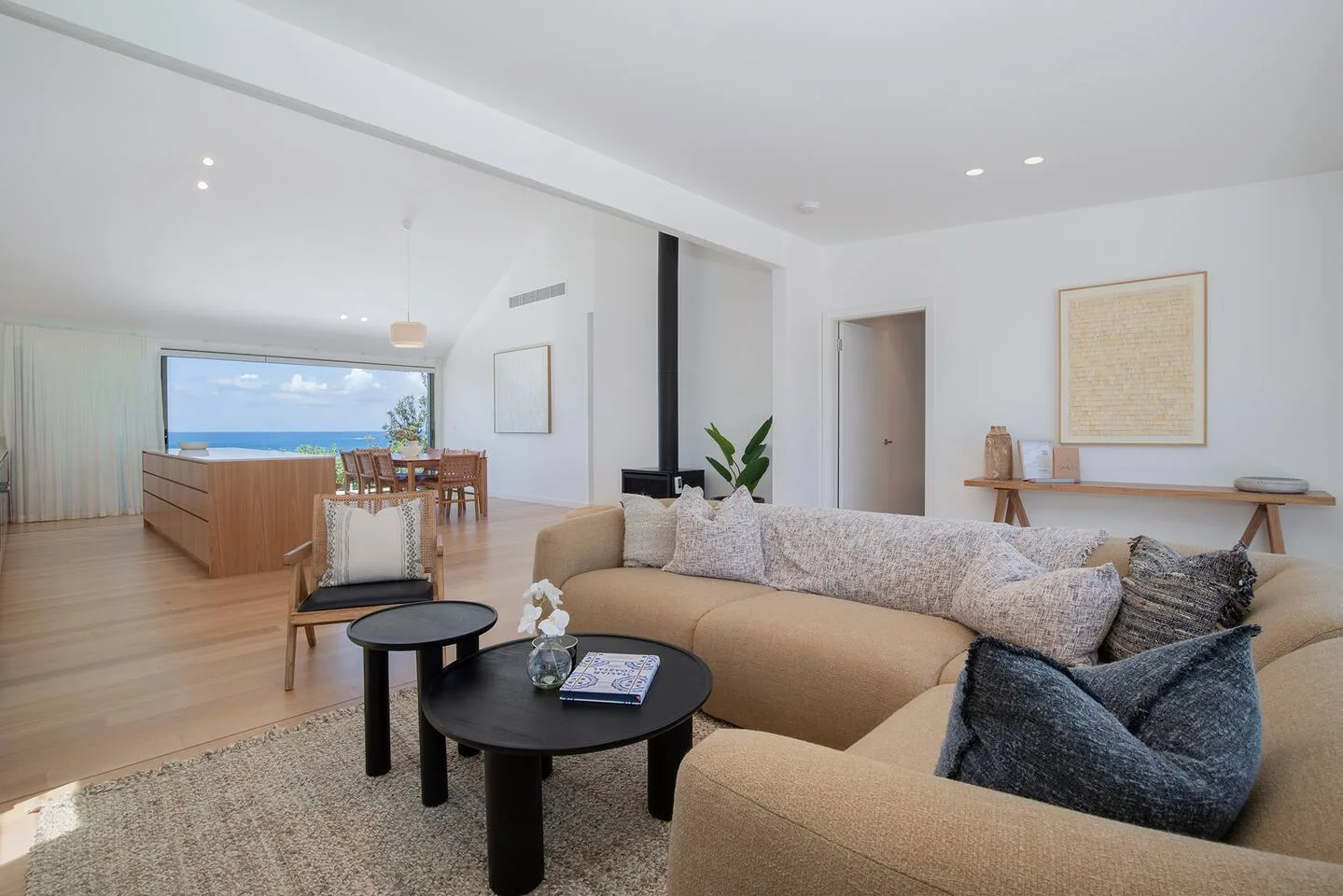 Una luminosa sala de estar con un sofá seccional beige y un comedor junto a la ventana.