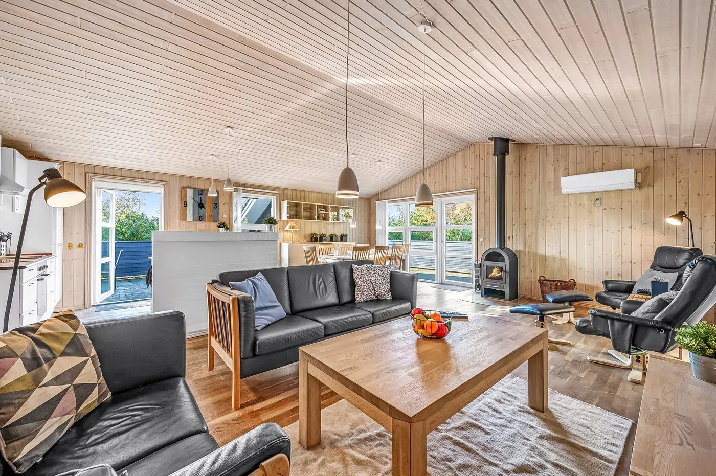 Sala de estar con cocina y comedor abiertos, con asientos y una mesa de madera.